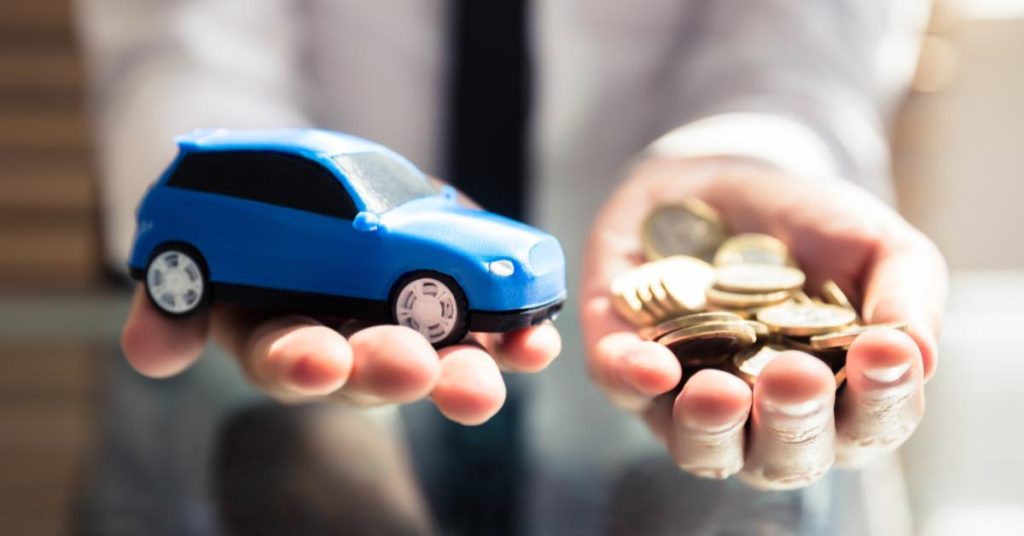 how to manage unexpected car repair costs UK A person in a suit holds out both hands, balancing a small blue toy car in one palm and a handful of coins in the other.