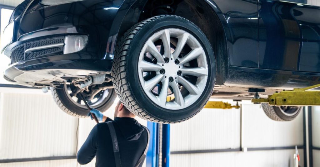 Payment flexibility as a competitive advantage for garages: A man works on a car that has been jacked up using garage equipment.