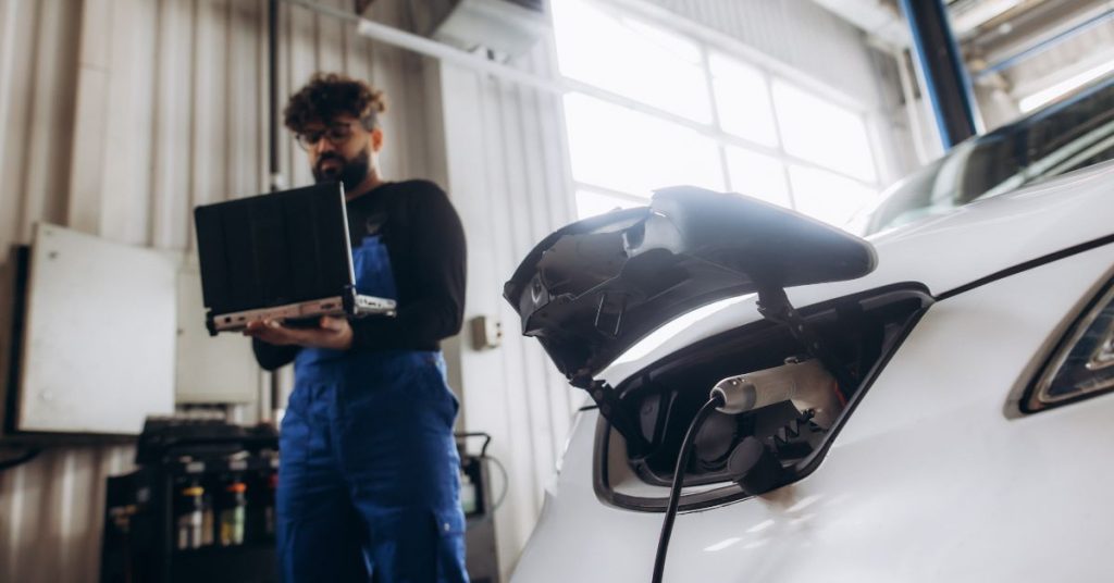 are chinese cars reliable? a man with a beard carries out laptop diagnostics on a white chinese electric car