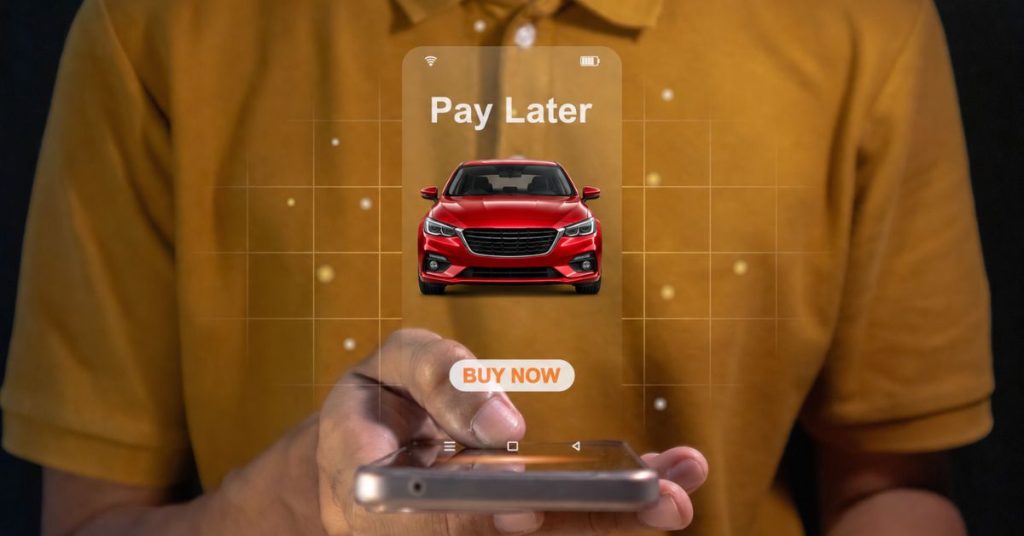 does spreading the cost of a car repair affect credit: Person holding a phone projecting a “Pay Later” screen with a red car and a Buy Now button.
